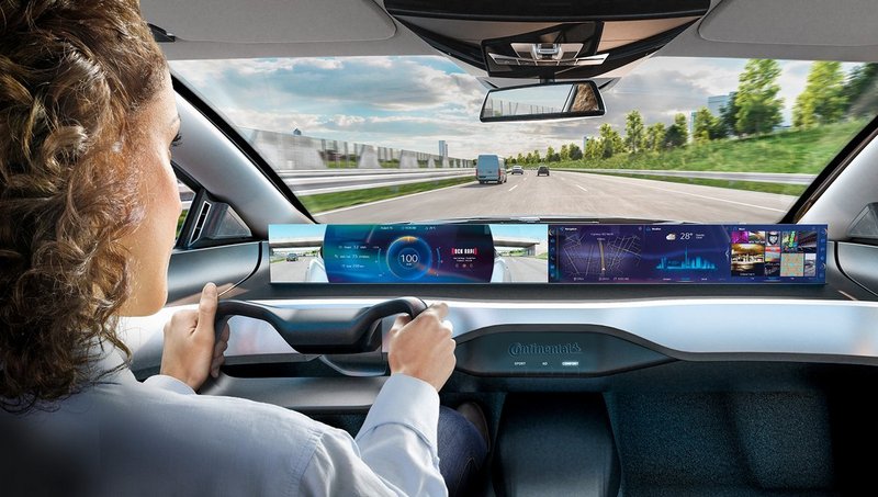 Eine Frau sitzt am Steuer eines futuristischen Konzeptautos und fährt eine Autobahn entlang