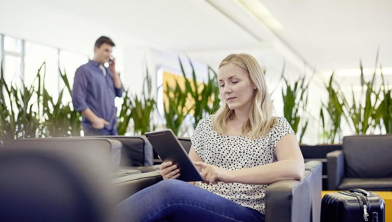 A woman is sitting in a lounge and is working with a tablet