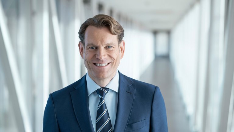 Portrait of a dark blond man in a blue suit in a hallway