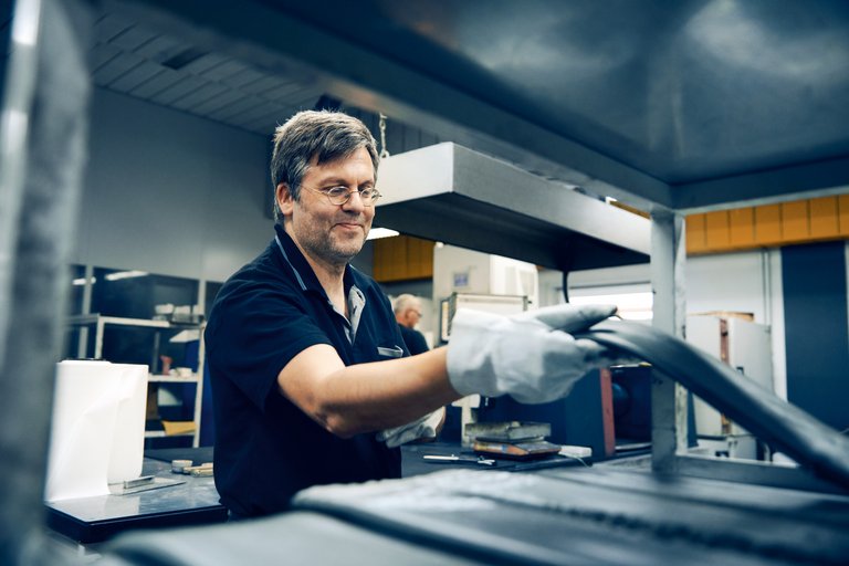 Ein Mann hantiert mit einem Gummi in einer Produktionshalle