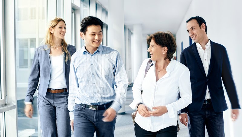 Four international colleagues are walking down the hallway togehter