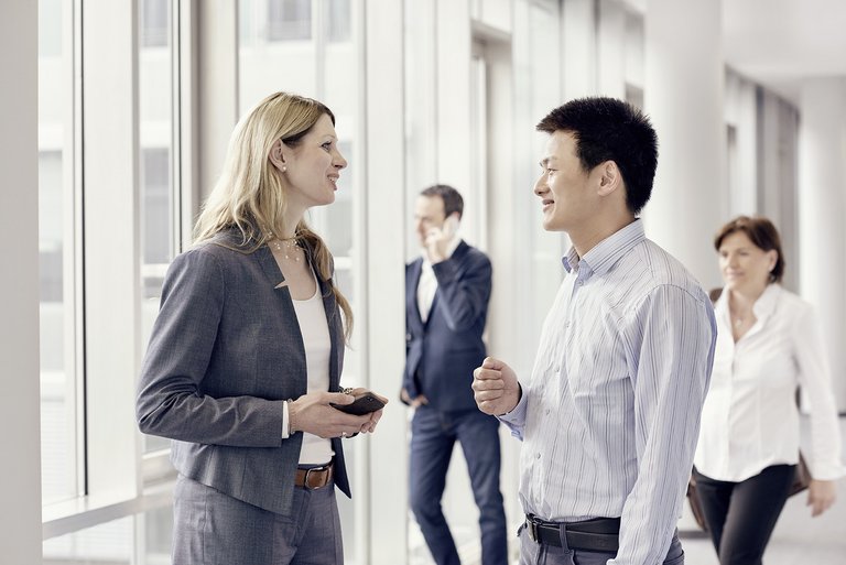 A woman and a man are talking to each other in a hallway