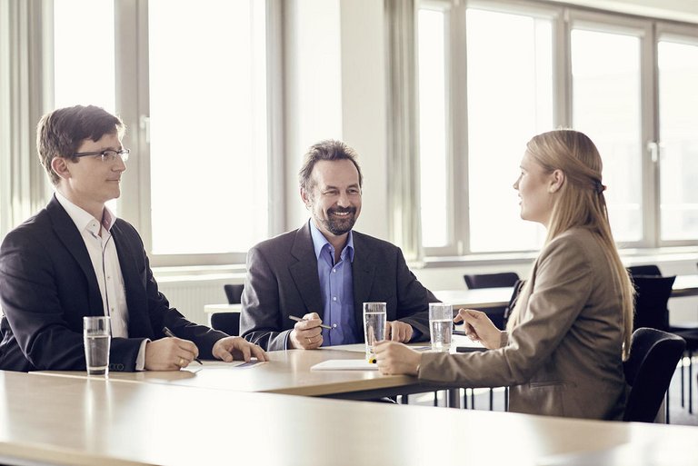 Two men and a woman have a job interview in a conference room