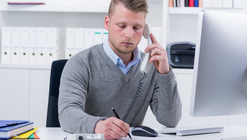 Ein Mann nimmt Notizen während einem Telefonats