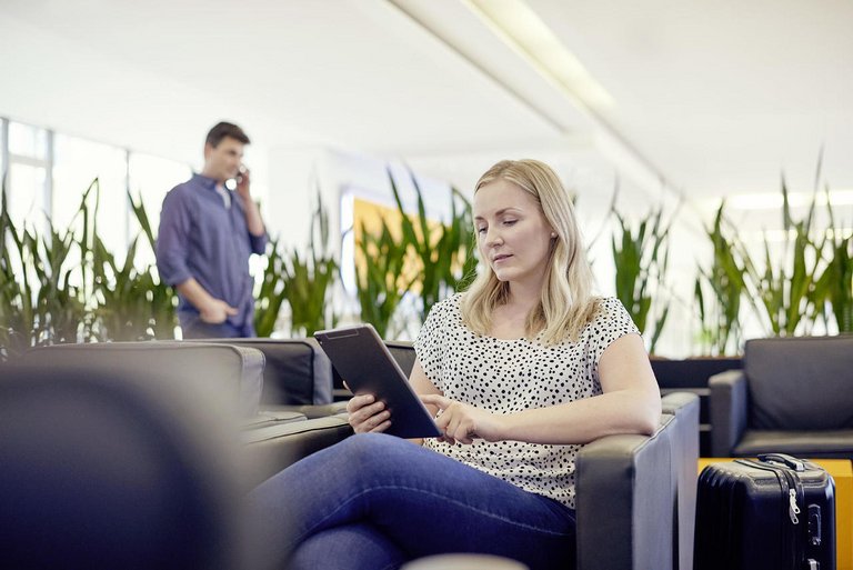 O femeie stă într-un cafenea și lucrează de pe o tabletă